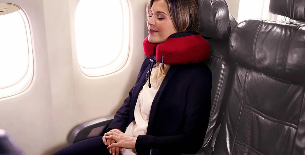 cô gái đang đeo gối du lịch Cabeau Evolution S3 màu đỏ trên máy bay