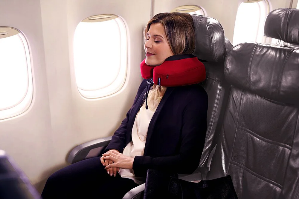 cô gái đang đeo gối du lịch Cabeau Evolution S3 màu đỏ trên máy bay